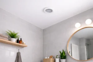 Bouche de VMC au plafond dans l’angle d’une salle de bain moderne, lumière naturelle