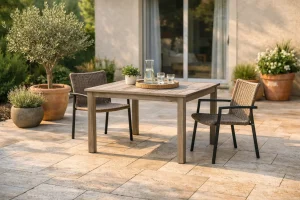 Terrasse en travertin clair aménagée avec table et chaises, lumière douce, façade en arrière-plan