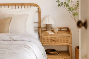 Table de chevet en rotin naturel près d’un lit dans une chambre douc