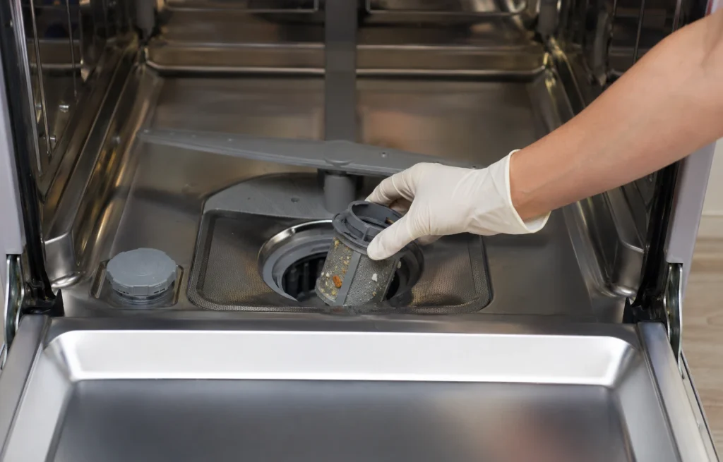 Main retirant le filtre au fond de la cuve d’un lave-vaisselle